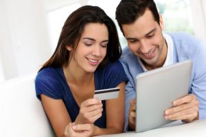 A couple making a payment using a credit via tablet